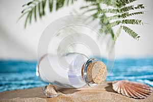 Stranded bottle message note with cork on a beautiful holiday beach with palms and sea shells