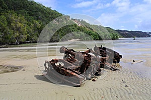 Stranded car wreckage on sandy beach