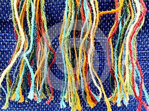 Strands of colorful threads against a blue hue