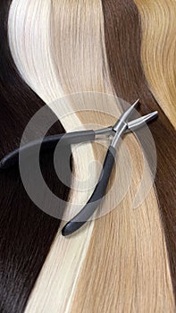 Strands of natural hair in different colors for extensions with tools. Hair color palette.