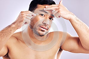 These strands are stepping out of place. Studio shot of a handsome young man tweezing his eyebrows.