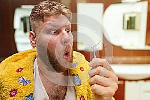 Strange adult man looks at the hair from his nose