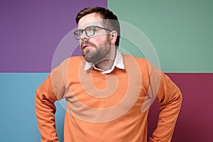Strange Caucasian man looks suspiciously and incredulously to the side with a bizarre grimace. Colorful background.