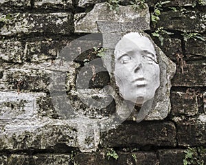 Strange Face Sculpture on a Brick Wall