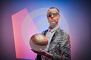 Strange guy in custom suit poses with golden ball in studio