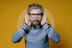 Strange hairy man tries something overheard having put hands to ears and with a bizarre expression on her face looking
