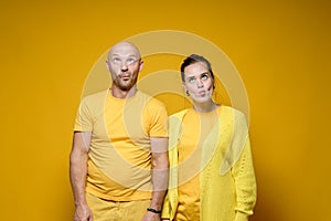Strange man and woman in yellow robes, made stupid faces. Bright background.