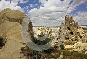 A strange, pointed rock with caves rises against the background of a blue sky