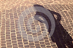 Strange shadow of a woman`s silhouette on an old stone road. Black shadow, female hand.