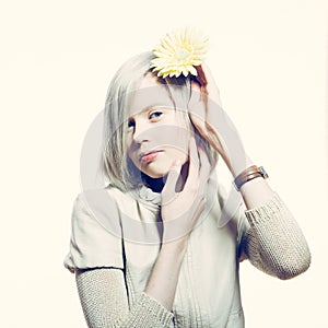 Strange slim blonde girl with a yellow flower in her hair.