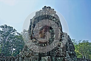 Strange statues at the top of the temple. In the clear sky, huge human faces