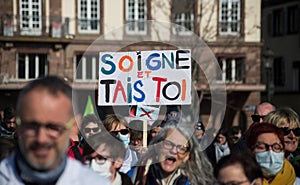 people protesting for the hospital with text in french : soigne et tais toi, in english : take care and shut up