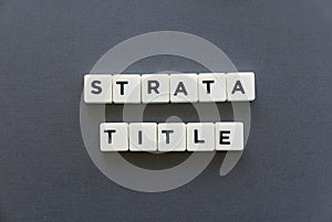 Strata title word made of square letter word on grey background.