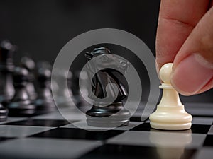 Strategic planning business competition concept. Hand holding white pawn moving playing chess board game. Leader and teamwork to