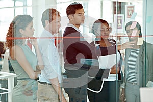 Strategies that are built for success. a group of businesspeople strategizing on a glass wipe board in their office.