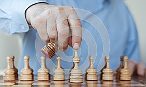 Strategy concept, hand of businessman moving wooden chess figure in play, management or leadership competition success background