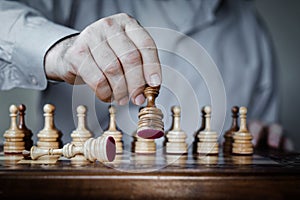 Strategy concept, hand of businessman moving wooden chess figure in play, management or leadership competition success background