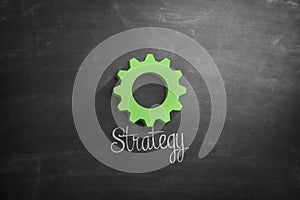 Strategy text with green cogwheel on blackboard