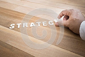 Strategy word with male hand on wood table.Business marketing