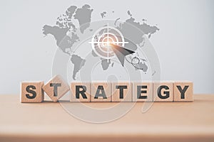 STRATEGY text on wooden cube blocks on world map background and rocket , target sign. Business target or goal success and winner