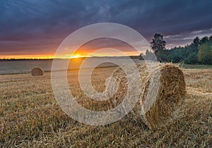Straw bales on field against sky