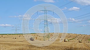 Straw bales on the field near high electricity pylons