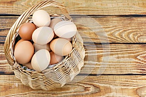 straw basket with eggs on wooden background.