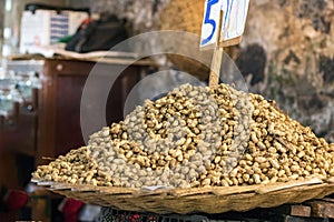 A straw basket full of peanuts for sale with the board price on the top at the Port Louis market in Mauritius