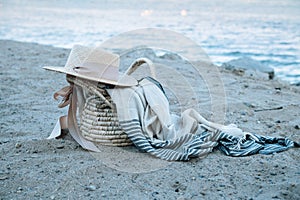 A straw basket with hat and a peshtemal cotton towel on a wild beach