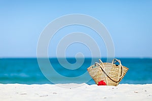 Straw beach bag on exotic white sand beach