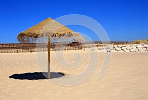 Straw beach sunshade, Deserted beach, Near Lisbon, Portugal.