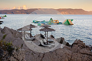 Straw beach umbrellas on the beach of Rabac, Croatia