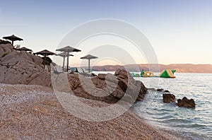 Straw beach umbrellas on the beach of Rabac, Croatia