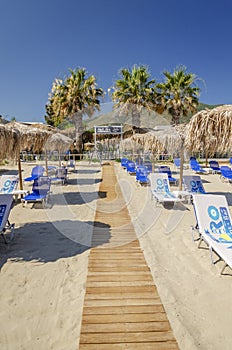 Straw beach umbrellas and sun chairs on a sandy beach on the east coast of Zakynthos island, Greece
