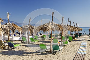 Straw beach umbrellas and sun chairs on a sandy beach on the east coast of Zakynthos island, Greece