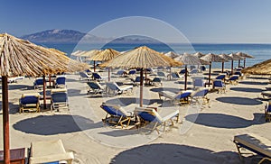 Straw beach umbrellas and sun chairs on a sandy beach on the east coast of Zakynthos island, Greece