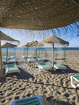 Straw beach umbrellas with sun loungers . Torremolinos in Spain