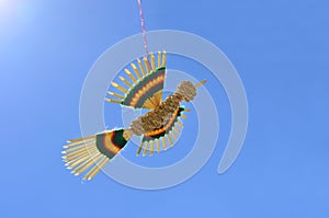 Straw bird flying on a thread against bright blue sky