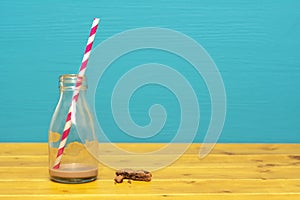 Straw and bottle with dregs of milkshake, and cookie crumbs