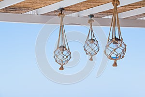 Straw cover the roof of a seaside terrace or veranda with hanging lantern and view to blue sky.many light bulbs