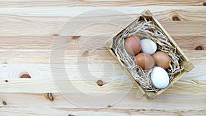 Straw and eggs in wooden crates on wooden background with copy space