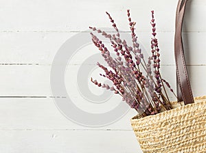 Straw handwoven beach shoulder bag with leather handles lavender flowers bouquet on white plank wood background. Provence style photo