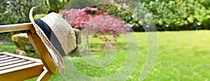 Straw hat on an armrest of a chair  in a garden