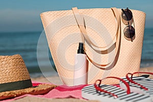 Straw hat, bag and other beach items on pink towel