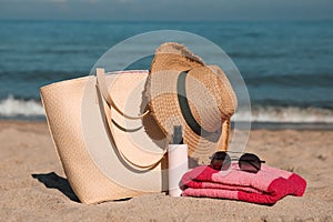 Straw hat, bag and other beach items on sandy seashore