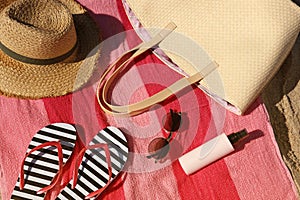 Straw hat, bag and other beach items on sandy seashore, closeup. View from above