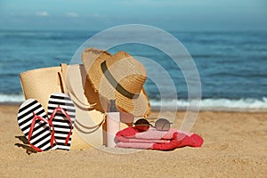 Straw hat, bag and other beach items on sandy seashore, space for text