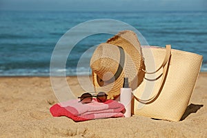 Straw hat, bag and other beach items on seashore, space for text