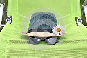 Straw hat with black glasses on a green chair