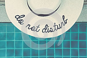 Straw hat with Do not disturb wording at the pool edge